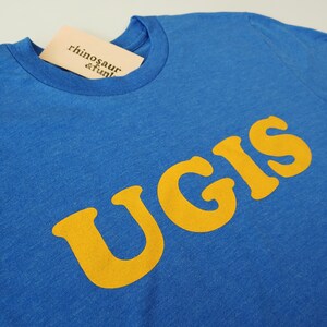 May include: A royal blue t-shirt with a yellow graphic that says "UGIS".