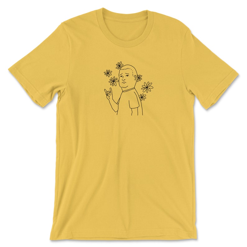 May include: A yellow t-shirt with a black line drawing of a person with a sad expression and flowers around their head. The person is making a rock and roll hand gesture.