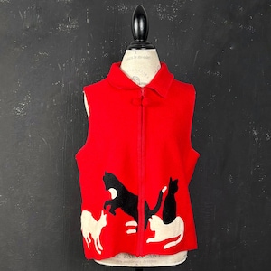 May include: A bright red sleeveless vest featuring a full-length front zip and a fold-over collar. The lower portion of the vest is decorated with three appliquéd cat silhouettes: one large black cat in the centre, one white cat on the left, and one white cat on the right.