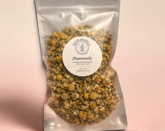 May include: A clear, resealable plastic pouch filled with dried yellow and white chamomile flowers. A circular white label on the front features the text "herbaholicz", "Chamomile", "dried german chamomile", and "for tea bath ritual".