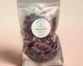 May include: A clear resealable pouch containing bath salts with visible dried pink rose petals and dark botanical pieces. A circular white label features the text Herbaholicz, Pink Goddess, bath salts, net wt. 4oz, and herbaholicz.com.