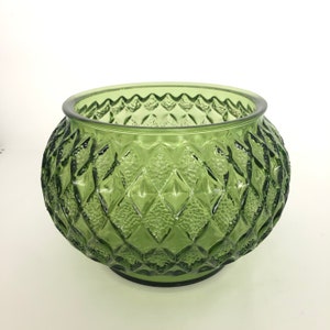 May include: A green glass bowl with a diamond pattern. The bowl is round and has a wide opening.