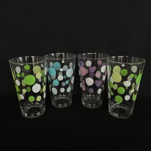 Puede incluir: Cuatro vasos de beber de vidrio transparente con un patrón de lunares. Los vasos tienen lunares de diferentes colores: verde, azul, morado y verde claro.