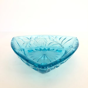 May include: A light blue glass triangular dish with a floral design.