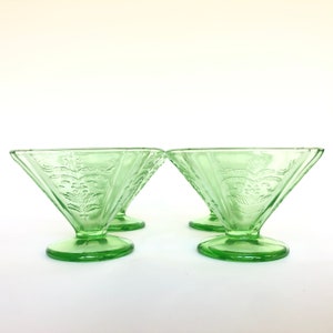 May include: Set of four green glass dessert dishes with a floral design. The dishes have a flared rim and a pedestal base.