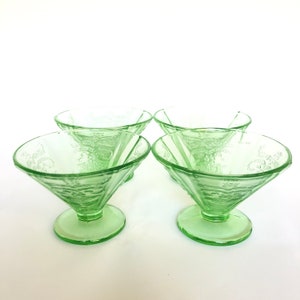 May include: Set of four green glass dessert bowls with a delicate floral pattern. The bowls have a flared shape and a short stem.