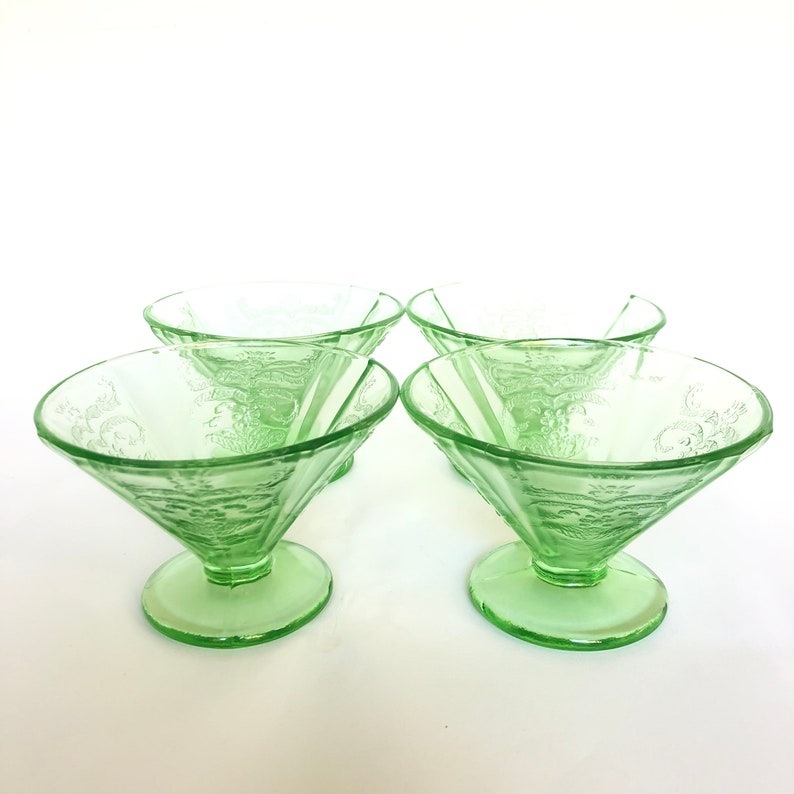 May include: Set of four green glass dessert bowls with a delicate floral pattern. The bowls have a flared shape and a short stem.