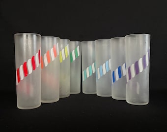 Pode incluir: Conjunto de oito copos de vidro fosco com listras coloridas. Os copos são de vidro transparente com acabamento fosco e têm um design de listras em várias cores, incluindo vermelho, laranja, amarelo, verde, azul e roxo.