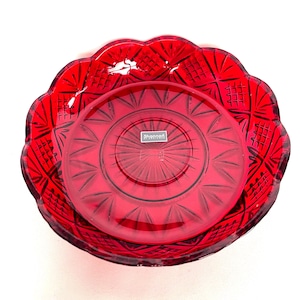 Può includere: Una ciotola di vetro rossa con bordo smerlato e un piatto abbinato. La ciotola e il piatto hanno un design in vetro tagliato. Il piatto ha la scritta "Shannon" su una piccola etichetta.