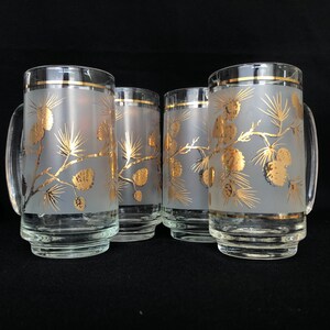 May include: Set of four frosted glass mugs with gold pine cone and branch designs. The mugs have a gold rim and a handle.