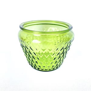Könnte beinhalten: Eine grüne Glasschale mit einem Rautenmuster. Die Schale hat eine abgerundete Form mit einem leicht ausgestellten Rand. Das Glas hat eine leuchtende, durchscheinende grüne Farbe. Die Schale wird wahrscheinlich für dekorative Zwecke oder als kleiner Pflanztopf verwendet.