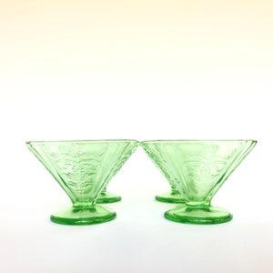May include: Set of three green glass dessert dishes with a floral design. The dishes have a flared, conical shape with a round base.