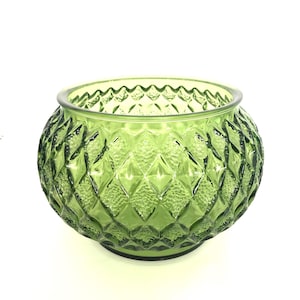 May include: A round, green glass bowl with a diamond pattern. The bowl has a wide opening and a slightly raised base. The glass has a textured surface and a scalloped rim. The bowl is suitable for decorative purposes.