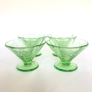 May include: Set of four green glass dessert dishes with a floral design. The dishes are in a vintage style and have a fluted edge.