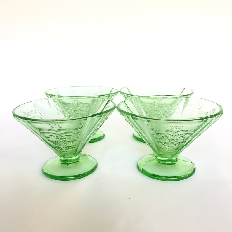 May include: Set of four green glass dessert dishes with a floral design. The dishes are in a vintage style and have a fluted edge.