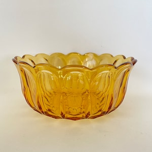 May include: A large amber glass bowl with a scalloped rim and a textured, fluted design. The bowl is ideal for serving salads, fruit, or snacks.