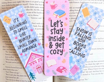 May include: Three decorative bookmarks with winter-themed designs. One bookmark has the text "It's Beginning to Smell Like Winter Small Town Romance." Another says "Let's Stay Inside & Get Cozy." The third reads "Snow is Falling and Books are Calling."