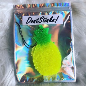 May include: A green and yellow pineapple-shaped car air freshener with the text "Don't Stink!" on a white label.