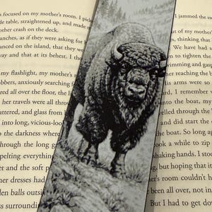 Puede incluir: Marcap&aacute;ginas en blanco y negro con una ilustraci&oacute;n detallada de un bisonte sobre una superficie rocosa. La imagen tiene una est&eacute;tica vintage, con una cordillera al fondo. Un accesorio para los amantes de la lectura.