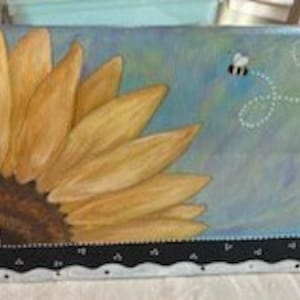 May include: A painted metal mailbox with a black and white checkered border. The front of the mailbox features a sunflower with a bee flying above it. The background is a light blue with a watercolor effect.