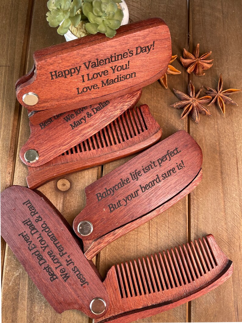 May include: Four wooden pocket combs with engraved messages. The top comb reads "Happy Valentine's Day! I Love You! Love, Madison". The second comb reads "We love Mary & Dallas". The third comb reads "Babycake life isn't perfect. But your beard sure is!" The fourth comb reads "Best Dad Ever! We Love You, Dad! Jesus Jr., Fernando, & Raul".