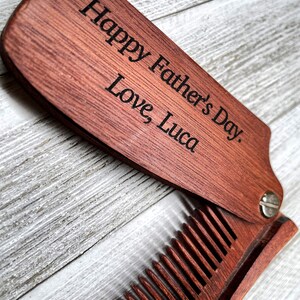May include: A wooden folding comb with a personalized message that reads "Happy Father's Day. Love Luca".