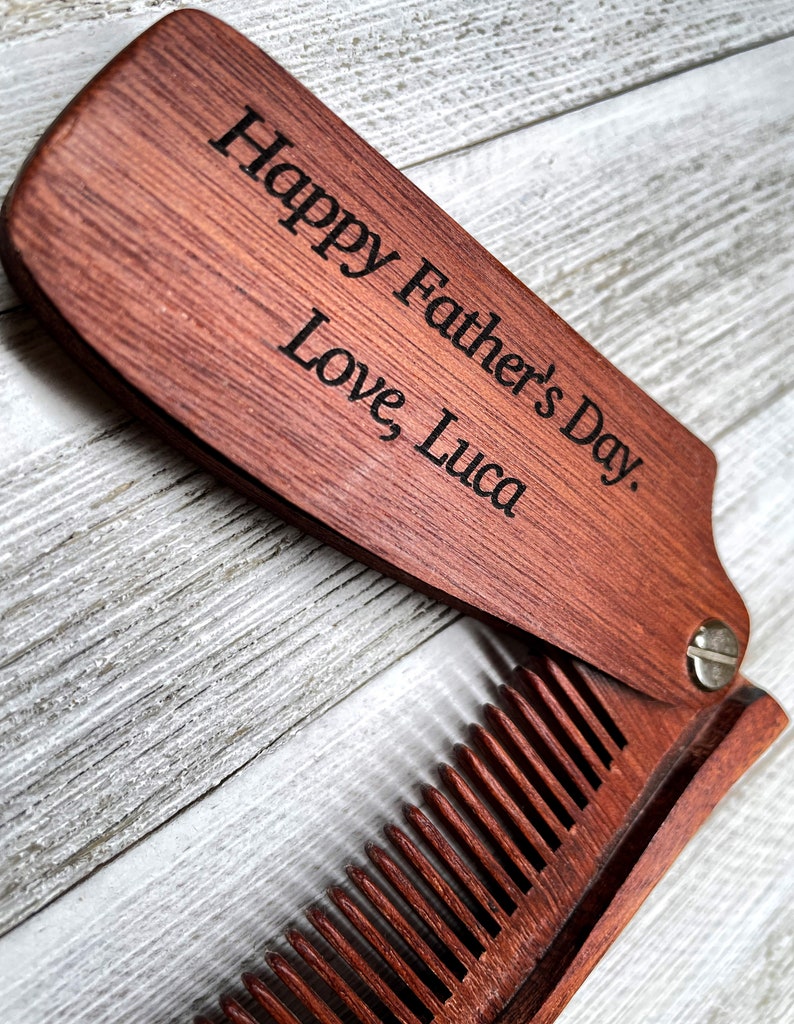 May include: A wooden folding comb with a personalized message that reads "Happy Father's Day. Love Luca".