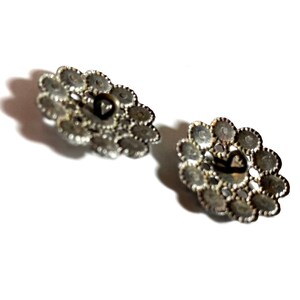 May include: Two silver-toned metal buttons with a decorative design of small circles. The buttons have a heart-shaped hole in the center.