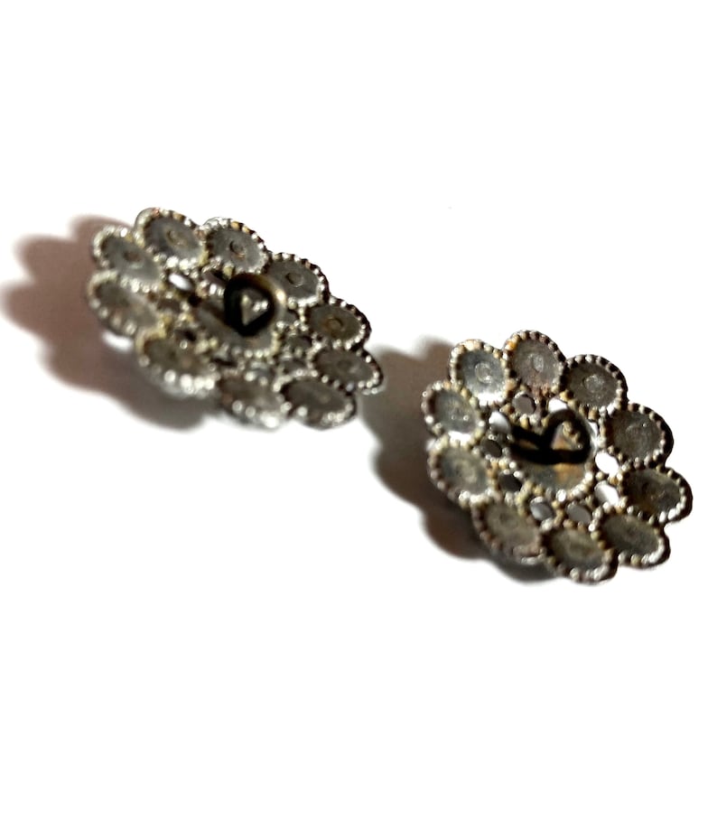 May include: Two silver-toned metal buttons with a decorative design of small circles. The buttons have a heart-shaped hole in the center.