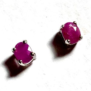 May include: A pair of silver stud earrings with round, pink ruby gemstones.
