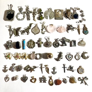 May include: A collection of silver charm pendants featuring a variety of designs, including hearts, crosses, butterflies, flowers, and animals. The charms are arranged in rows on a white background.
