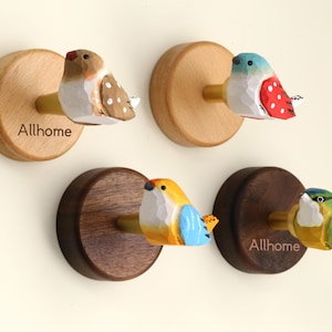 May include: Four wooden bird-shaped wall hooks. Each hook features a different colorful bird design, mounted on a round wooden base. The text "Allhome" is visible on two of the bases. These decorative hooks are ideal for adding a touch of nature to any room.