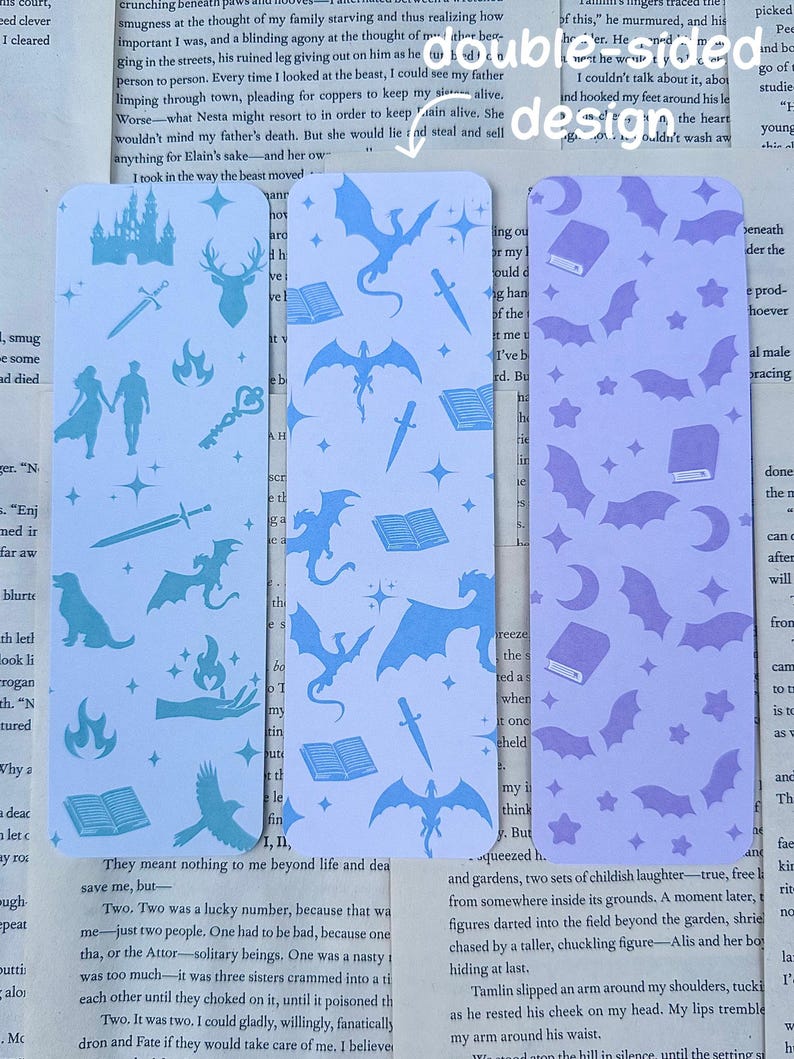 May include: Three rectangular bookmarks with double-sided designs. One is light blue with castle, sword, and dragon motifs. Another is light blue with dragon, book, and sword patterns. The third is lavender with bats and book designs.