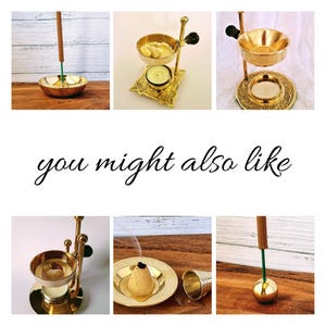 May include: A set of four gold metal incense holders. The holders are in different styles, including a round holder with a small incense stick, a holder with a round top and three legs, and a holder with a round top and a handle. The holders are all on a wooden surface.