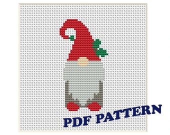 May include: A red and white gnome cross stitch pattern with a green holly sprig. The pattern is framed in a red frame and the words "PDF PATTERN" are printed in blue below the gnome.