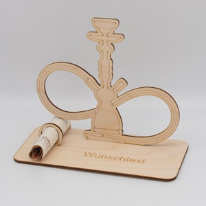 Könnte beinhalten: Holzständer mit einer Ausschnittform einer Wasserpfeife, einem Platz zum Einlegen eines gerollten Geldscheins und dem Text "Wunschtext".