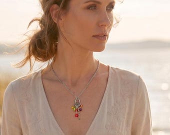 May include: A silver-toned chain necklace featuring a central charm pendant. The pendant consists of a circular metal ring adorned with multiple dangling beads in vibrant shades of red, yellow, green, and purple, creating a colourful accent.