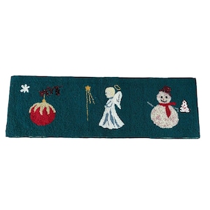 May include: A teal green Christmas-themed rug with a red and gold ornament, a white angel, and a snowman with a red scarf.