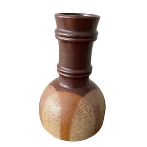 May include: A brown ceramic vase with a wide, round base and a narrow neck. The vase has a speckled, textured finish with brown and gold accents.