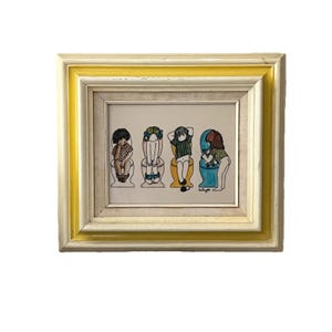 May include: Framed artwork featuring four cartoon figures seated on toilets. The figures are depicted with various hairstyles and clothing patterns, including floral and striped designs. The frame is a combination of white, gold, and cream colors.