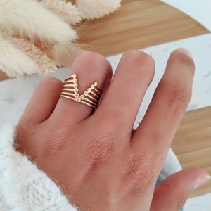 Puede incluir: Anillo de oro con un diseño en forma de V hecho de múltiples bandas con pequeños acentos redondos.