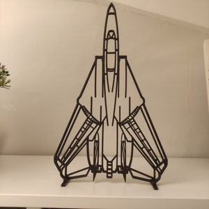 May include: A black metal model of a fighter jet with a long, pointed nose and swept wings. The model is standing on a white shelf.
