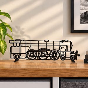 May include: A black metal silhouette of a steam locomotive train featuring intricate cut-out details of the wheels, boiler, and cabin. The structure is supported by two small feet, allowing it to stand upright on a flat surface.