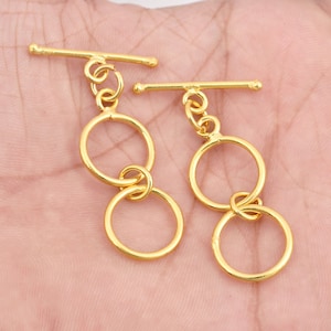 May include: Two gold-toned toggle clasps with double circle designs. Each clasp features a bar with a sliding toggle.