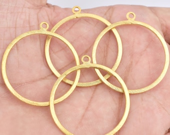 May include: Four gold-toned metal circle pendant blanks with a textured finish. Each blank has a small loop at the top for attaching a chain or string.