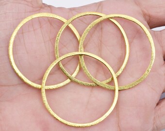 May include: Four gold-colored metal rings, stacked and overlapping, with a textured surface.