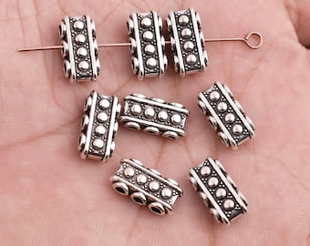 May include: A set of eight silver-toned metal spacer beads with a textured design. The beads are rectangular in shape and have a series of small, raised dots around the edges.