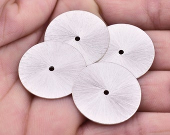 May include: Four silver watch dials with a radial brushed finish and a small hole in the centre.