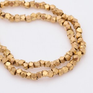 May include: A strand of gold-colored faceted beads. The beads are small and have a slightly irregular shape.