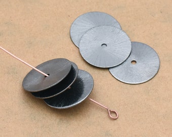 May include: Four silver metal discs with a hole in the center, stacked on top of each other. A thin copper wire is threaded through the hole in the top disc.